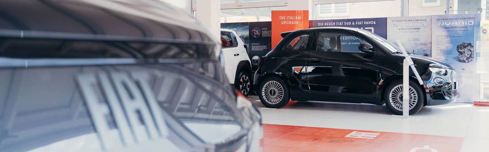 Mehrere Fahrzeuge stehen im Ausstellungsraum des Autohauses Weis. Im Fokus ein Fiat 500 Elektro
